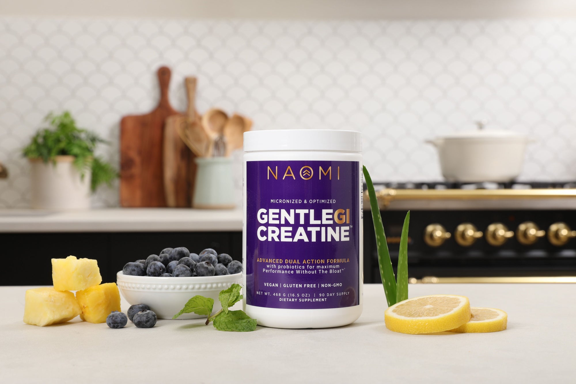 Container of Naomi Gentlegluten Creatine on a kitchen counter with fruits and plants.