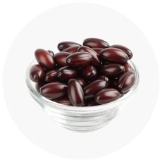 Glass bowl filled with dark red astaxanthin capsules on a white background