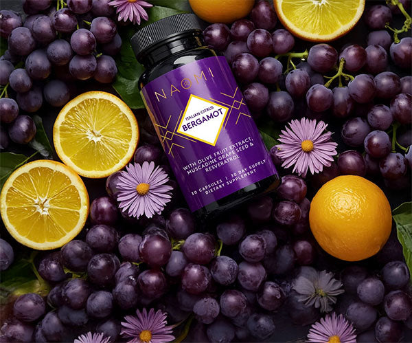 Bottle of NACMI Bergamot supplement surrounded by purple grapes, lemons, and flowers.