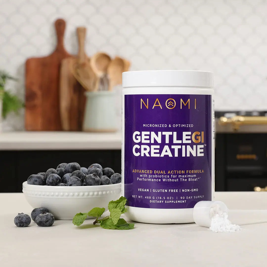 Supplement container labeled 'Gentle GI Creatine' by Naomi on a kitchen counter with blueberries.