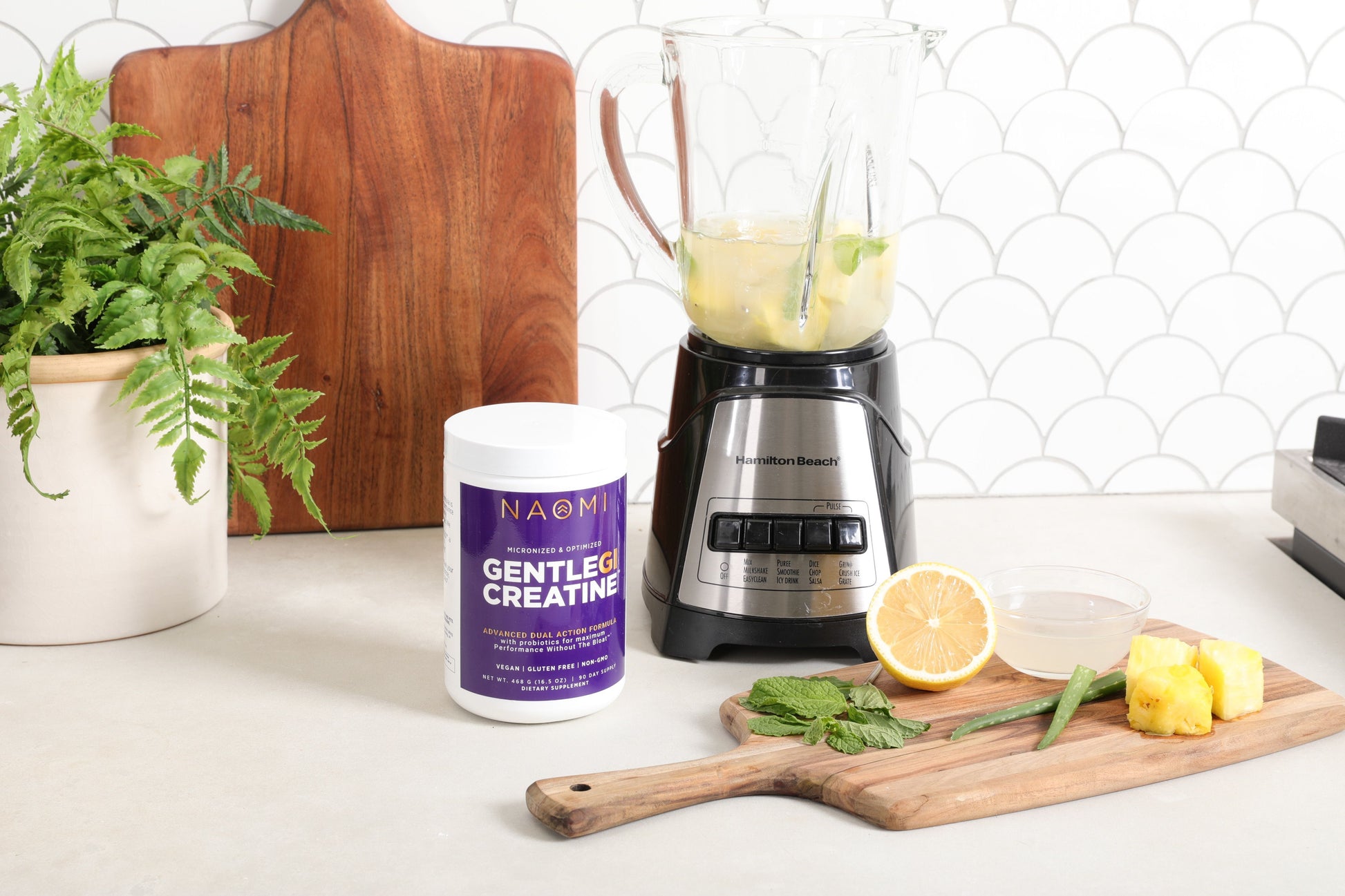 Blender with ingredients on a counter next to a NAOMI Gentle Creative supplement container.