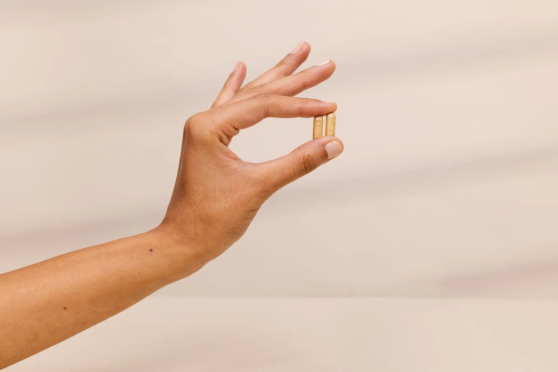 Hand holding a small gold object against a plain background